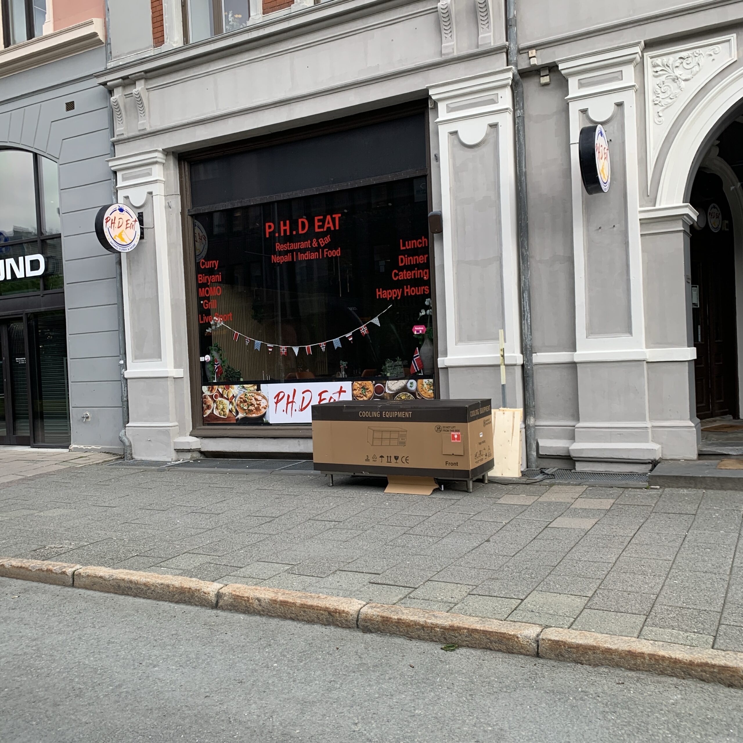 Kafé/spisested som har navnet "P.H.D EAT" i store røde bokstaver klistret på vinduet.